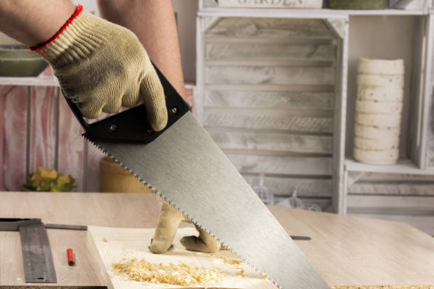 charpentier sciant une planche avec une scie en bois de main. - manual operation photos et images de collection