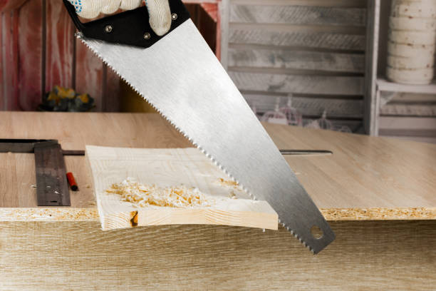 Carpenter sawing a board with a hand wood saw. stock photo