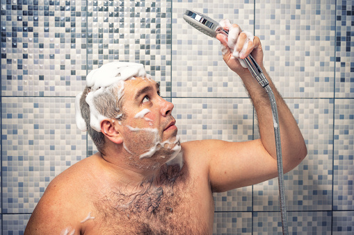 un hombre de 30-40 años de edad en una espuma se para en el baño, con ganas de una ducha, el agua no se vierte. fallo en el suministro de agua photo