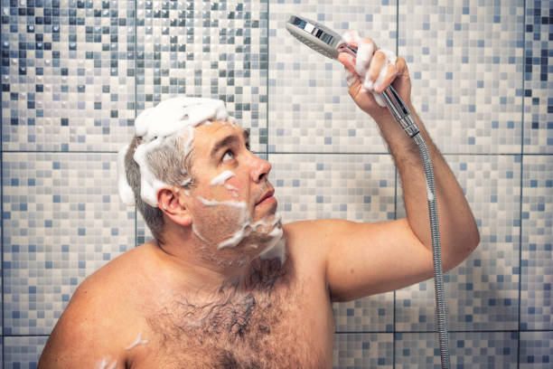 泡で30-40歳の男は、シャワーを楽しみにして、バスルームに立って、水が注がれていない。水供給の失敗 - 痩せ地 ストックフォトと画像