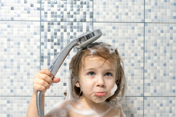 un bambino di 4 anni è coperto di schiuma nella vasca da bagno in mano che tiene una doccia, non c'è acqua, il bambino è sconvolto. il bambino non può lavare via il sapone, rottura del tubo dell'acqua. - 4 5 years foto e immagini stock