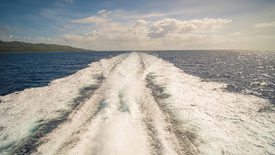 A trail of sea water foam follows the ferry to the island of Palawan. Philippines. Shooting in motion