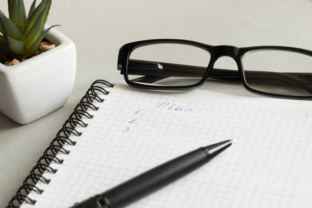 istock a plan is written in a notebook. Near glasses and a flower pot 1224855196