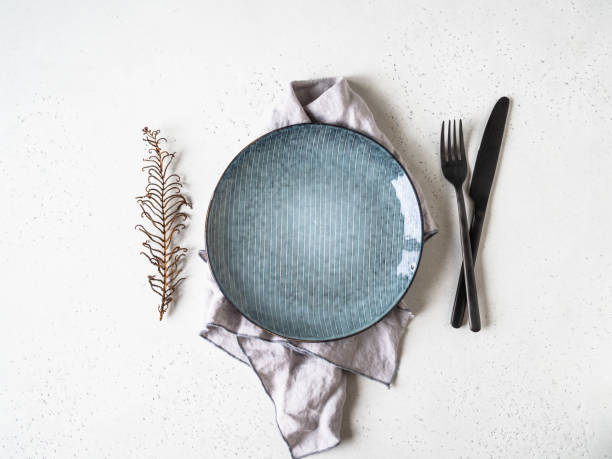istock Rustic table setting with plate, napkin and black utensil on white table. Top view. 1224858093