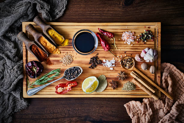 Variety of allspice ingredients and condiments for food seasoning on cutting board in old fashioned kitchen Variety of allspice ingredients and condiments for food seasoning on table in old fashioned kitchen. Ingredients set on a large size cutting board Cardamom stock pictures, royalty-free photos & images