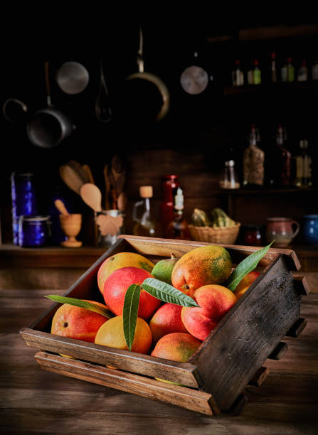 Tropical fruits. Group of ripe mangos in a crate on a rustic table
