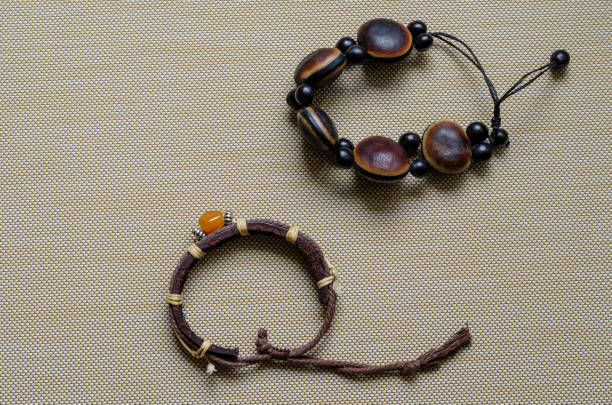 Handmade bracelets for women on a beige textured background. Brown bracelets made of leather and wood close-up. Free space for text. View from above.