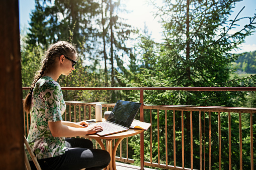 Teenage girl is sitting on balcony of a small wooden cabin in mountains. The girl is doing homework and listening to music.
BMPCC4K, RAW, Q0