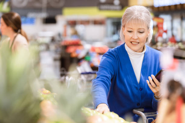 istock While holding smart phone, senior woman selects produce 1224859606