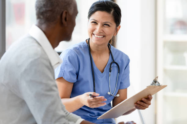 istock Nurse holding clipboard smiles at unrecognizable senior man 1224859651