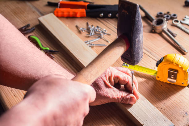 a nail hammered by a man a nail hammered by a man. on a workbench where there are other tools. for use in DIY topics, services, for handymen work tool nail wood construction stock pictures, royalty-free photos & images