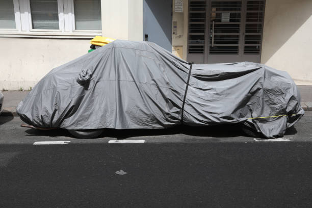istock old car covered with grey protection in street 1224865627