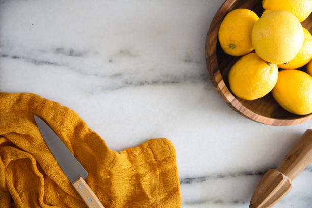 Fresh Lemons with kitchen utensils on a marble surface