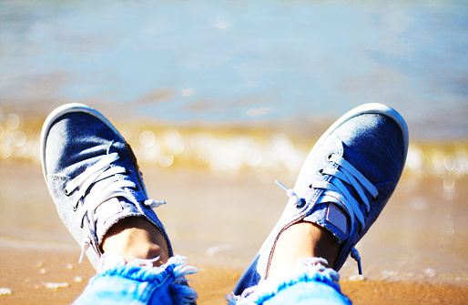 Beach Holiday: Tennis Shoes on Feet at Water's Edge