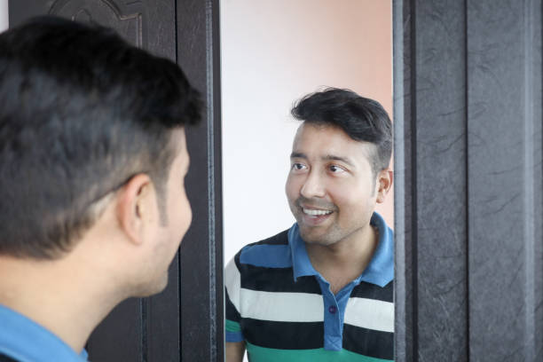 istock a man looking at his reflection in mirror smiling in happy mood. 1224869812