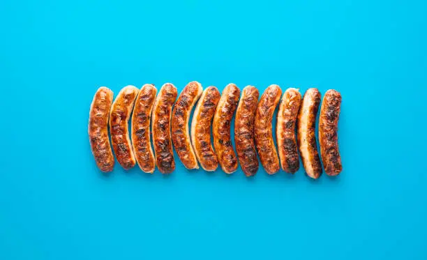 Above view with grilled german sausages, alligned on a blue background. Authentic grilled nuremberger bratwurst