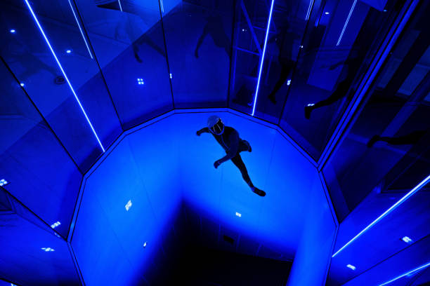 A man flier doing stunts in an indoor wind tunnel with neon lights
