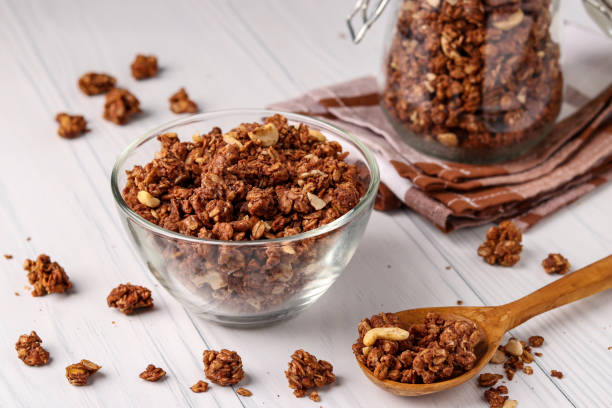 Granola crispy muesli with natural honey, chocolate and nuts in a glass bowl against a white background, healthy food, horizontal orientation stock photo