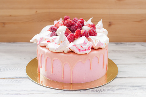 Pink cheese cake with melted chocolate, meringues, fresh raspberries and strawberries.