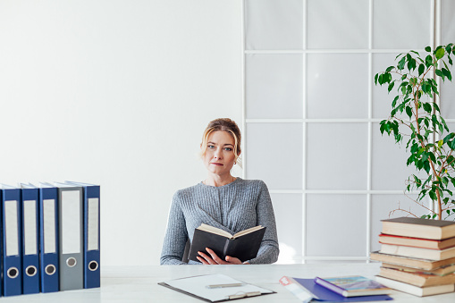beautiful woman sits at desk with teacher's books