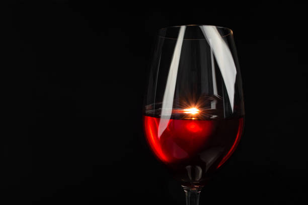 red wine in a glass on a high leg on a black background.