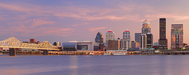 Panoramic view of the skyline of Louisville - the largest city in the commonwealth of Kentucky - as seen at dusk from across the Ohio river.