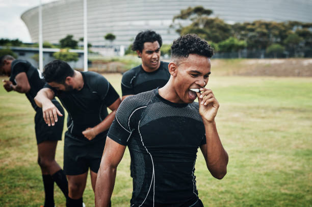 It's half-time Cropped shot of a handsome young rugby player removing his mouthguard during half-time on the field mouthguard stock pictures, royalty-free photos & images