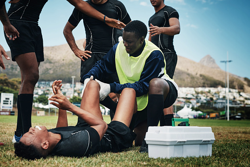 Cropped shot of a young rugby player receiving first aid assistance on the field