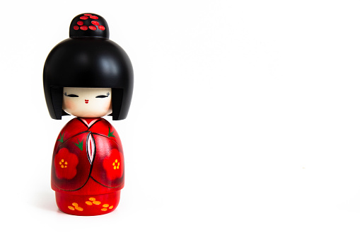 Kokeshi doll in red kimono on white background
