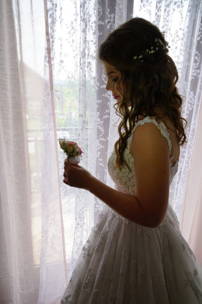 istock Side view portrait of bride with flower looking trough window 1224888731