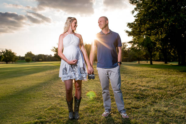 family portrait of pregnant parents to be with back lit sunlight rays. - couple human pregnancy sunset walking imagens e fotografias de stock