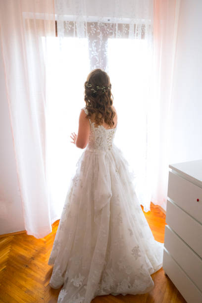 istock Back view portrait of bride looking trough window 1224888779