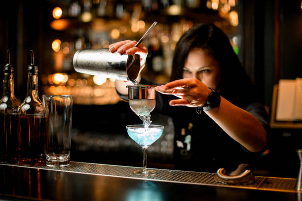 istock bartender pours cocktail from shaker into glass using sieve. 1224890939