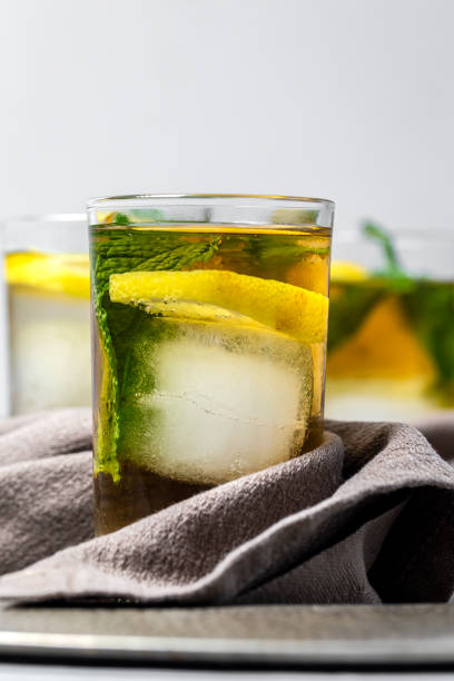 Refreshing glasses of tea with ice, mint and lemon wedges