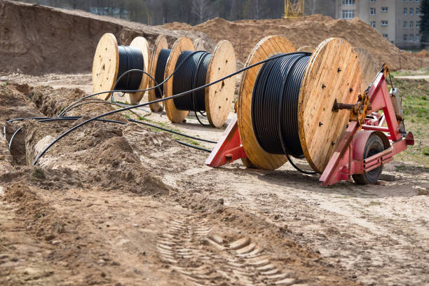 plusieurs bobines en bois avec câble d’alimentation posé dans la tranchée. concept d’approvisionnement en électricité pour les projets de construction. - câble photos et images de collection