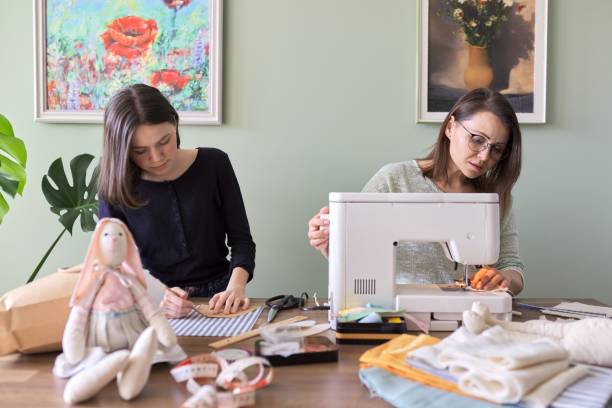 семейное хобби ручной работы и досуг, мать и дочь вместе шьют - sewing women tailor teenage girls стоковые фото и изображения