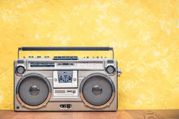 レトロな古いポータブルステレオブームボックスラジオ受信機は、80年代頃のフロントコンクリートテクスチャーイエローウォールの背景からカセットレコーダーを備えています。リスニン� - 1980s style hip hop rap 1990s style ストックフォトと画像