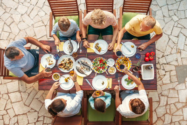 gran cena familiar multigeneracional en proceso.  mesa con comida y manos. consumo de alimentos y familia multigeneracional imagen de concepto de imagen top view. - prepared fish seafood barbecue grilled fotografías e imágenes de stock