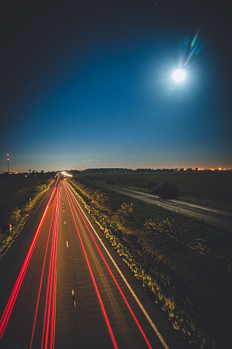 Slow shutter of cars lights on highway with full moon.