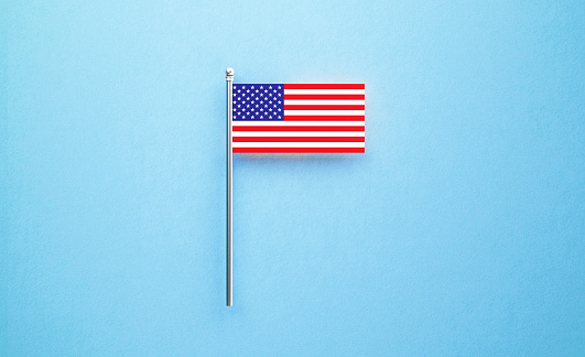 Tiny American flag on blue  background. Horizontal composition with copy space. Directly above. Flat lay.