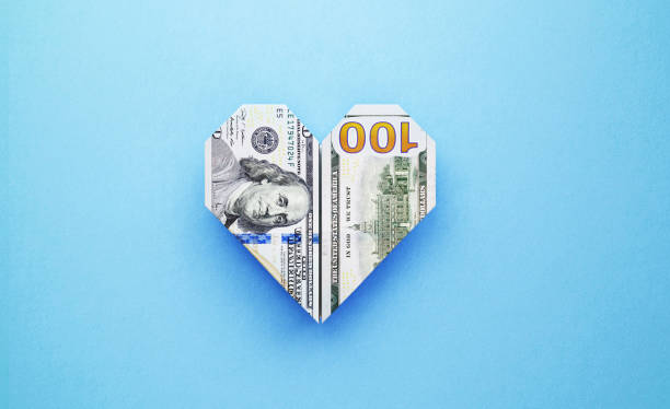 origami herz form mit hundert amerikanischen dollar bill auf blauem hintergrund gemacht - one hundred dollar bill stock-fotos und bilder