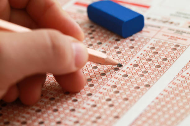 istock Students hand doing exams quiz test paper with pencil drawing selected choice on answer sheets at school 1224900701