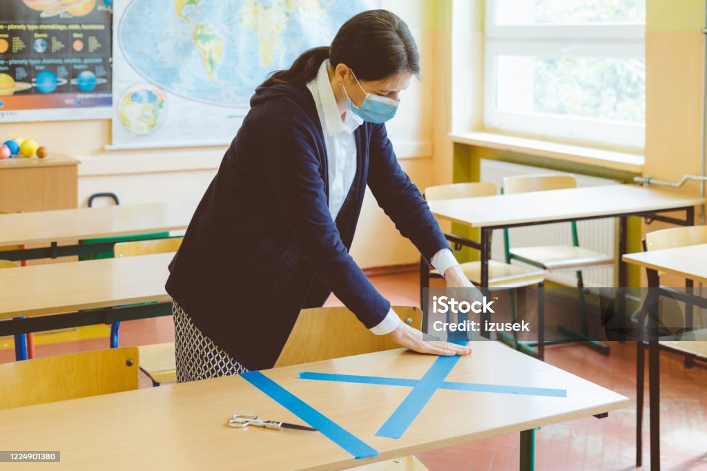 Covid-19 The teacher marks empty sits in the classroom The teacher marking places in the classroom that are to be empty after students return to school after the coronovirus pandemic. Covid-19 Classroom Stock Photo