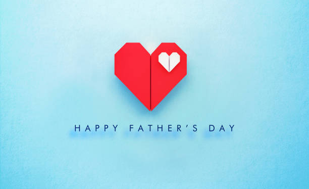 White origami heart sitting inside of a red origami heart on turquoise background.  Happy Father's Day written below the heart. Horizontal composition with copy space. Father's Day concept.