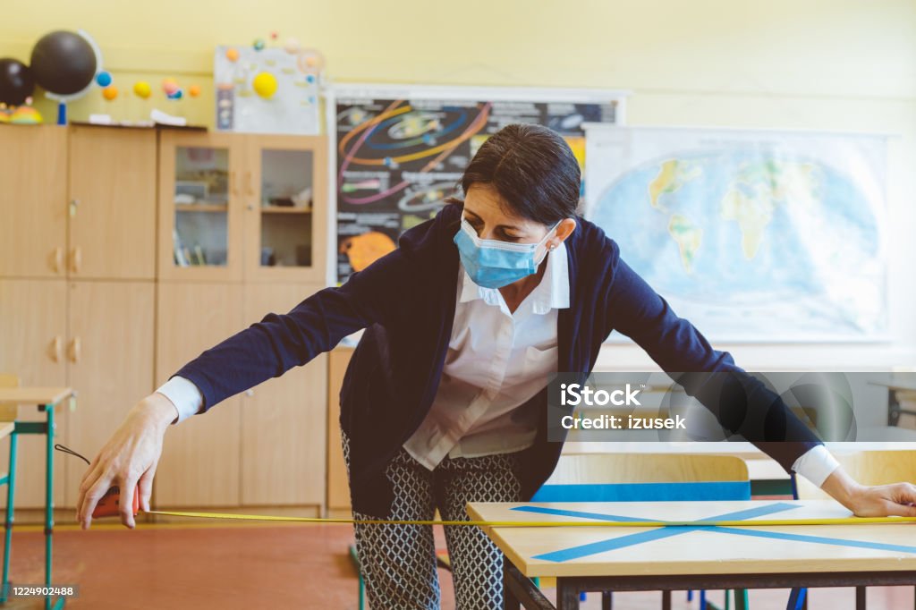 Covid-19 The teacher marks empty places in the classroom The teacher measuring and marking places in the classroom that are to be empty after students return to school after the coronovirus pandemic. Covid-19 Classroom Stock Photo
