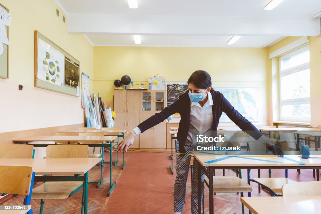 Covid-19 The teacher marks empty places in the classroom The teacher measuring and marking places in the classroom that are to be empty after students return to school after the coronovirus pandemic. Covid-19 Coronavirus Stock Photo