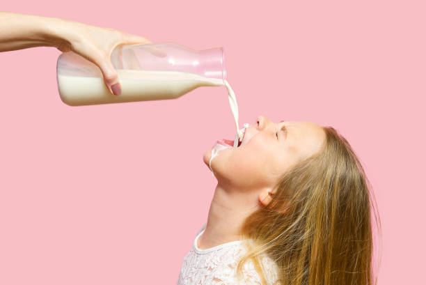 happy girl buvant du lait de la bouteille isolated on pink background. le lait obtenu par la bouche des filles - got milk photos et images de collection