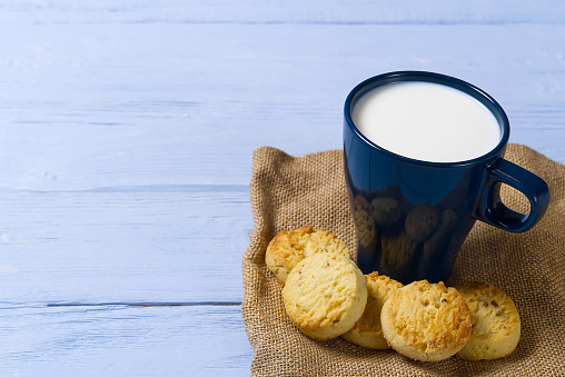 mug of warm milk and cookies before bed. Blue cup with fresh milk and tasty cookies