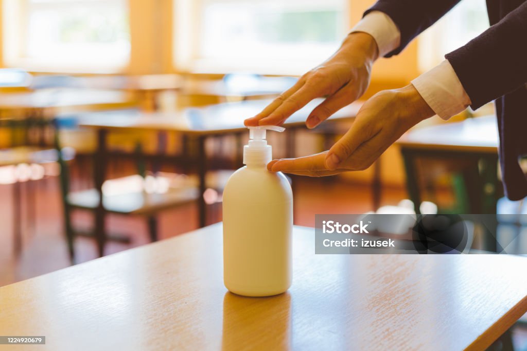 Using hand sanitizer in the classroom School students  using hand sanitizer after entering a classroom. Avoidance Stock Photo