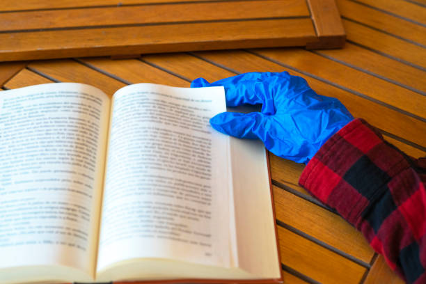 woman manicured hand with red nails read the book wrapped in a blanket